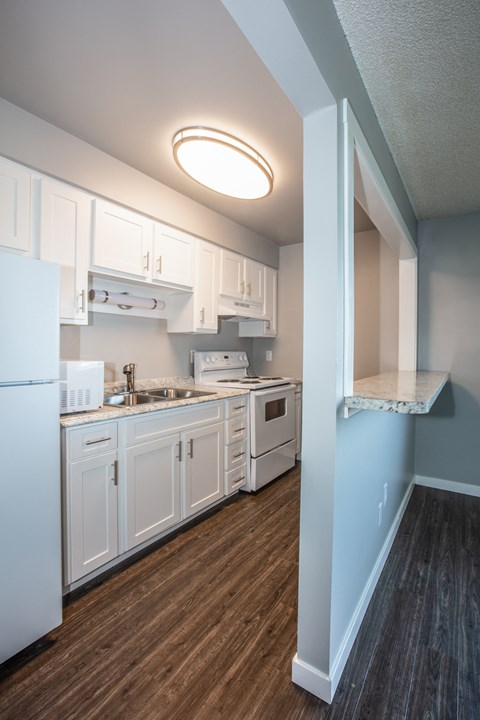 a kitchen with white cabinets and appliances and a wood floor